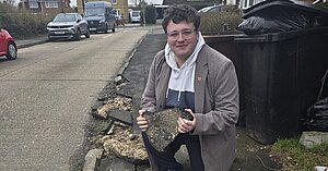 Cllr Kieron Franks holds a piece of the disintegrating footway